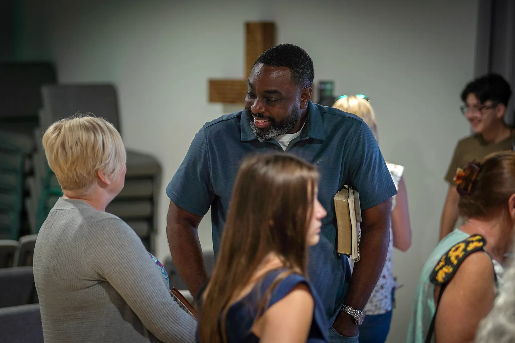Three people talking, a Bible under one arm