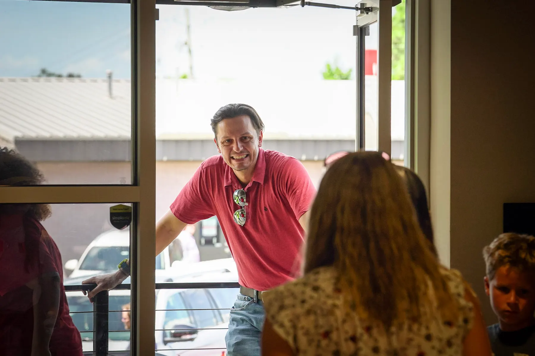 A greeter welcoming somebody in at the door